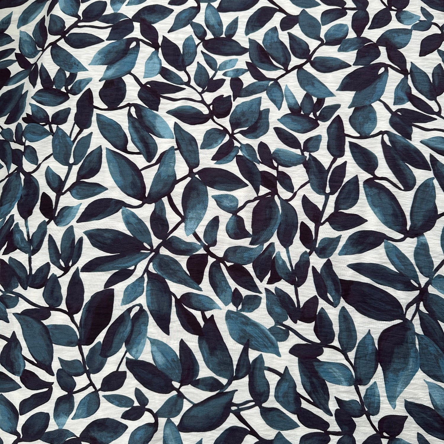 Pattern of blue leaves on an off white fabric background
