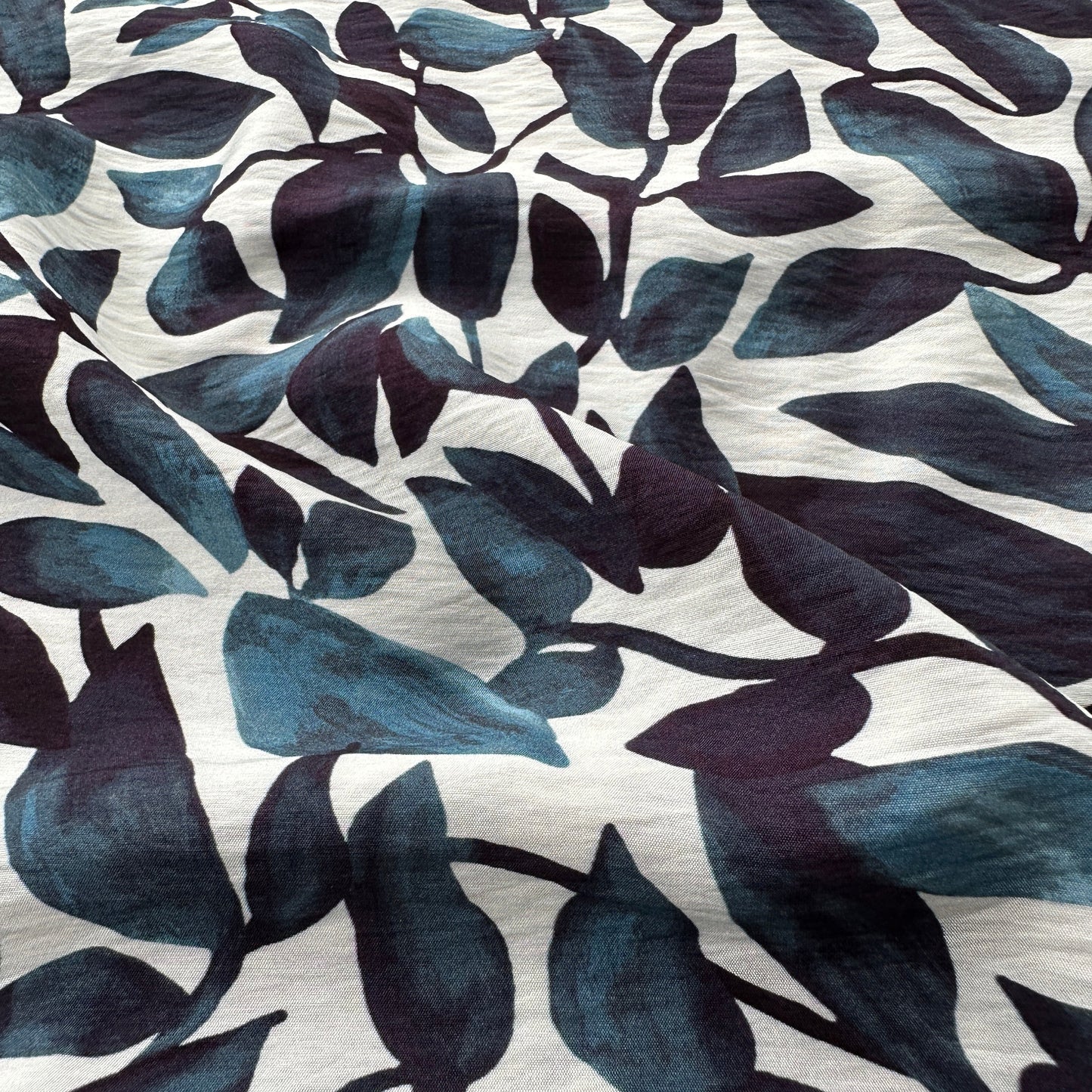 Fabric with a pattern of dark blue leaves on an off white background