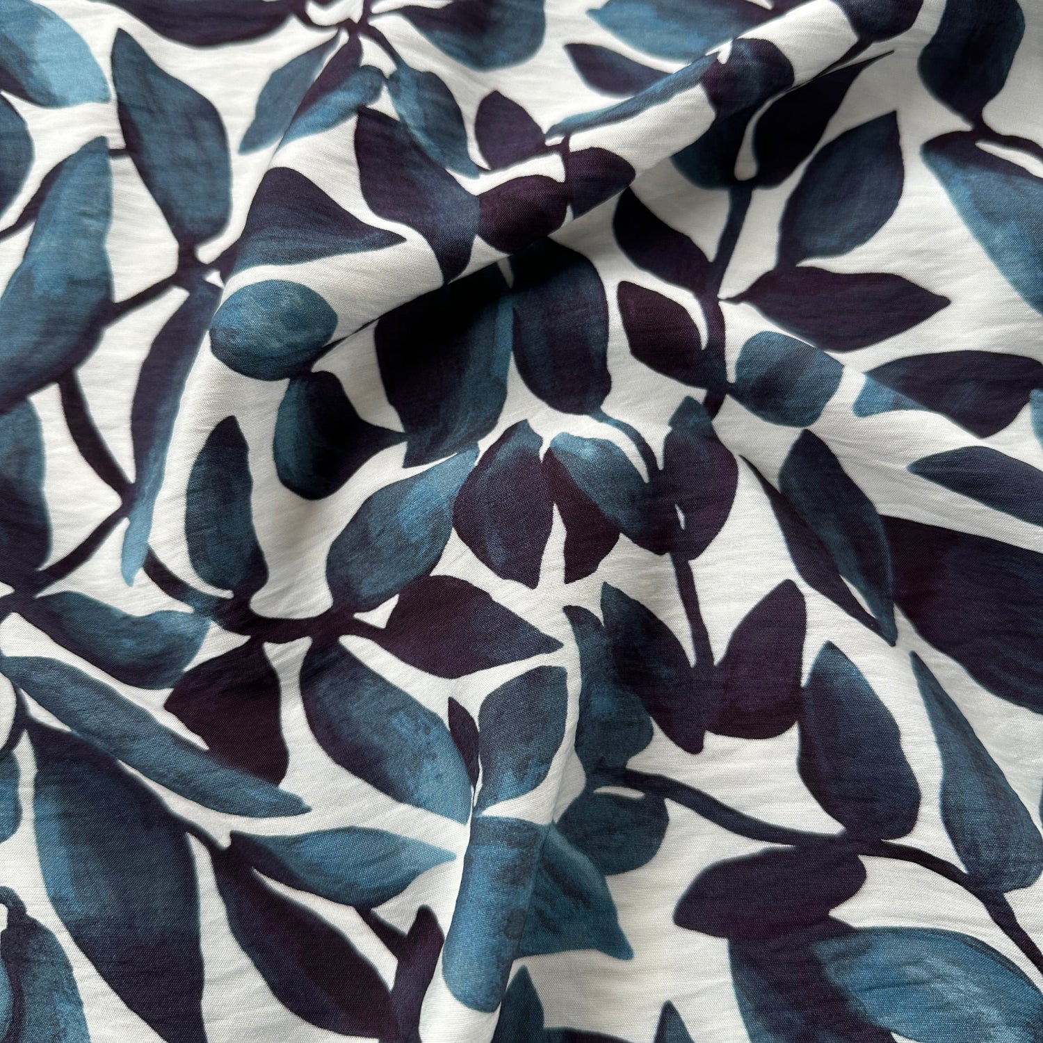 Close-up of fabric with blue leaf pattern on a white background