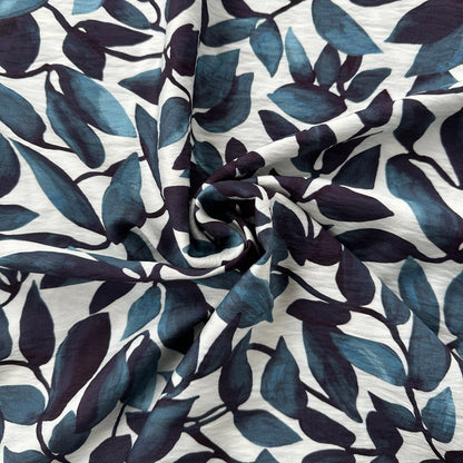 Swirl of fabric with blue leaf pattern on an off white background