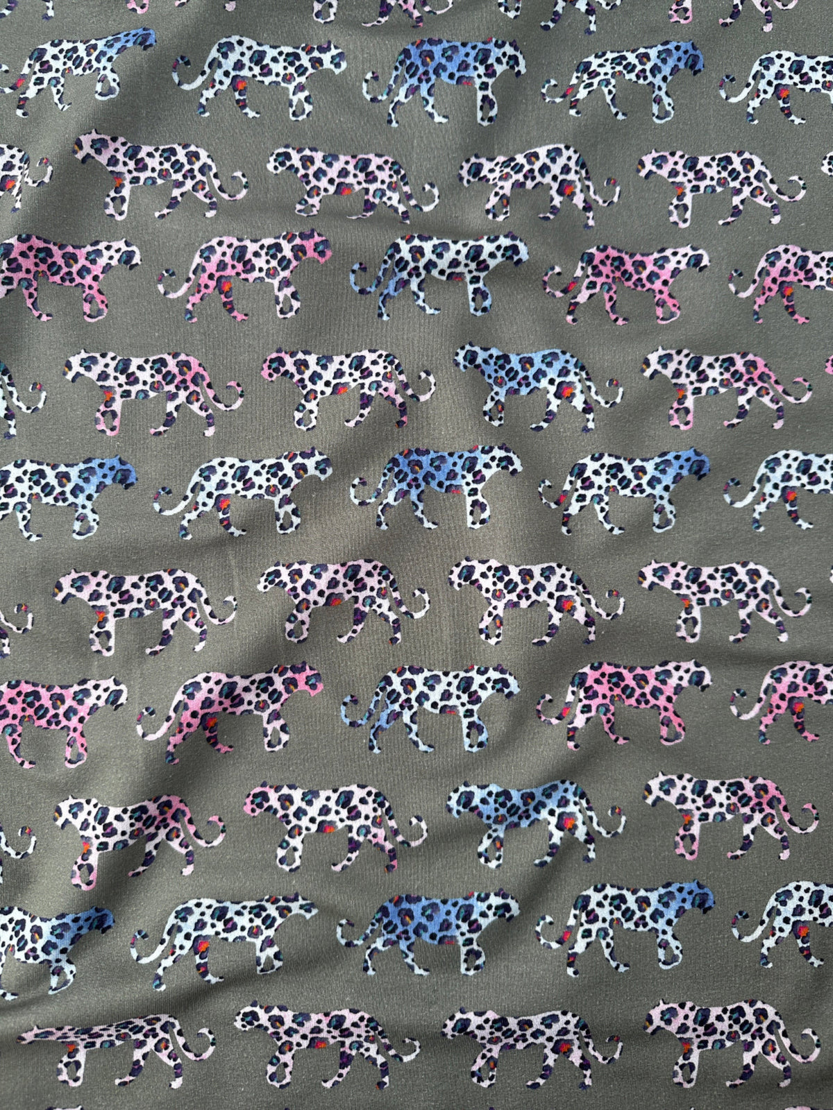Grey fabric with pink and blue leopards across it