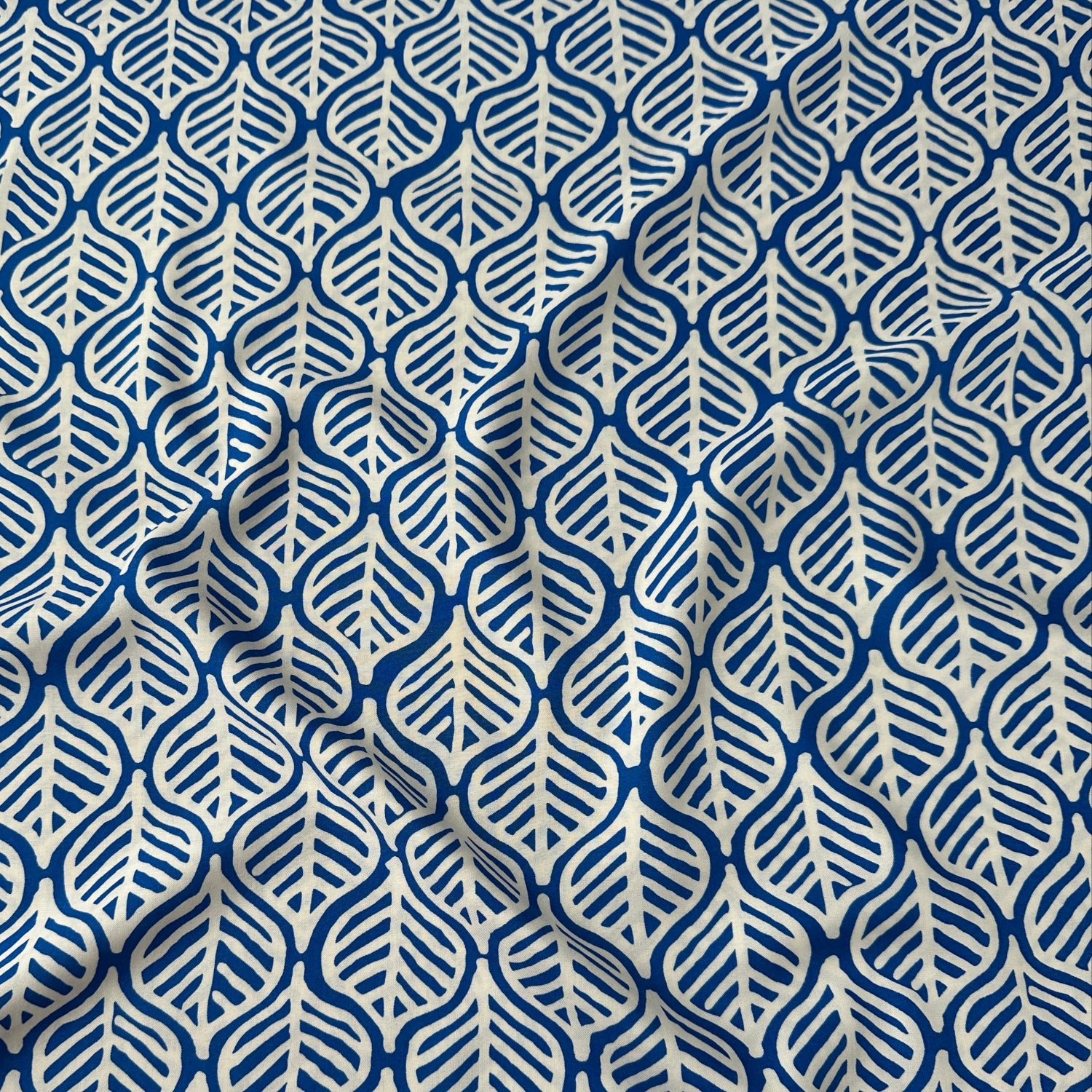 White leaves on cobalt blue viscose dressmaking fabric
