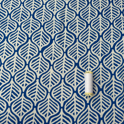 White leaves on cobalt blue viscose fabric with reel of thread for scale